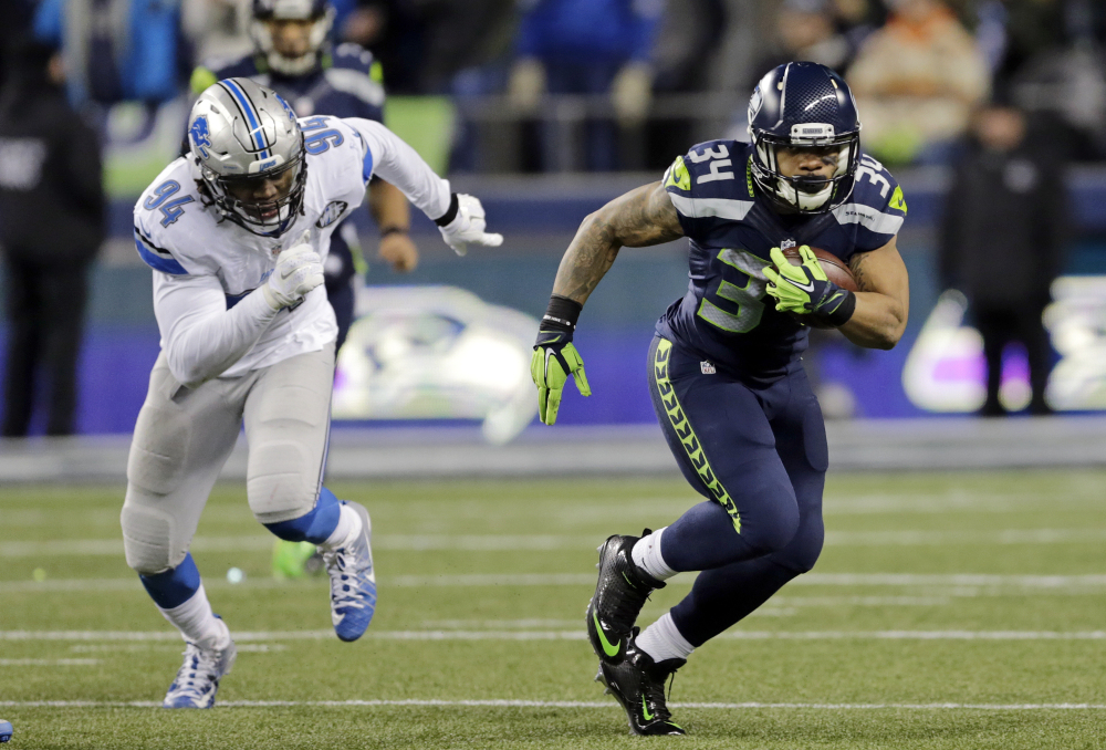 Seattle running back Thomas Rawls, right, is pursued by Detroit's Ezekiel Ansah in the first half of Saturday night's NFC wild-card game in Seattle. Rawls rushed for 161 yards on 27 carries and scored a touchdown as Seattle advanced to the next round against Atlanta. (Associated Press/Stephen Brashear)
