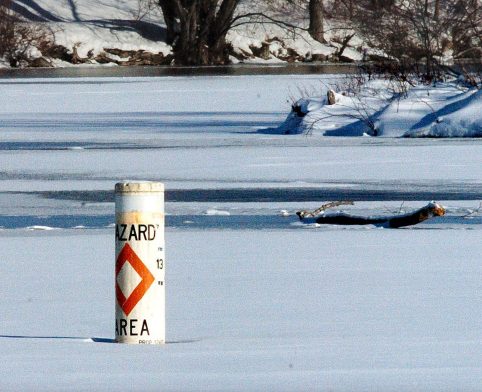 A hazard buoy marks the area near the outlet dam on Messalonskee Lake where a moving current reduces the thickness of the ice. Richard Dumont died Saturday after his snowmobile broke through the ice at the spot where a log, in background, was left.
