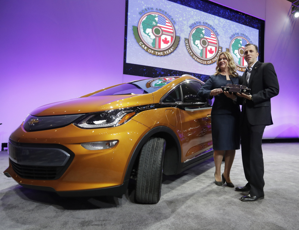 GM Executive Pam Fletcher and Chief Engineer Josh Tavel hold the trophy Monday after the Chevy Bolt, left, was named top car at the North American International Auto show.