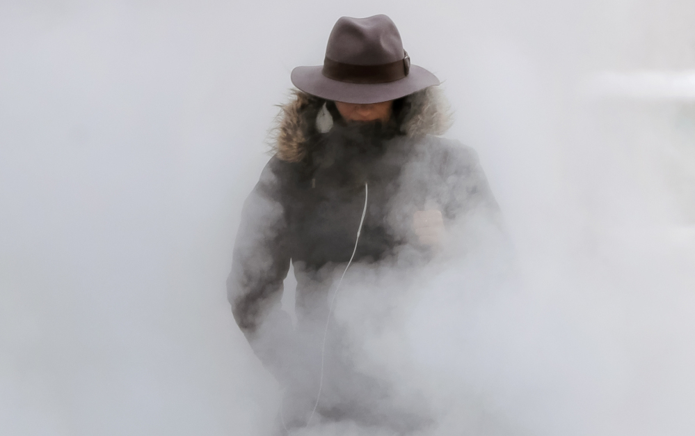 A woman walks through steam from an underground vent as temperatures dropped below minus 20 degrees Tuesday in Bucharest, Romania. In Albania, it snowed in the southern city of Saranda for the first time in 32 years.