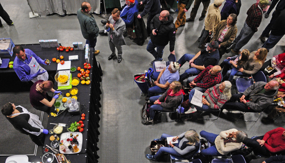 Cynthia Finnemore-Simonds, bottom left, Elizabeth Simonds and Jim Darroch, Backyard Farms director of marketing, do a cooking demonstration featuring Backyard Farms tomatoes during the Maine Agricultural Trades Show on Tuesday at the Augusta Civic Center.