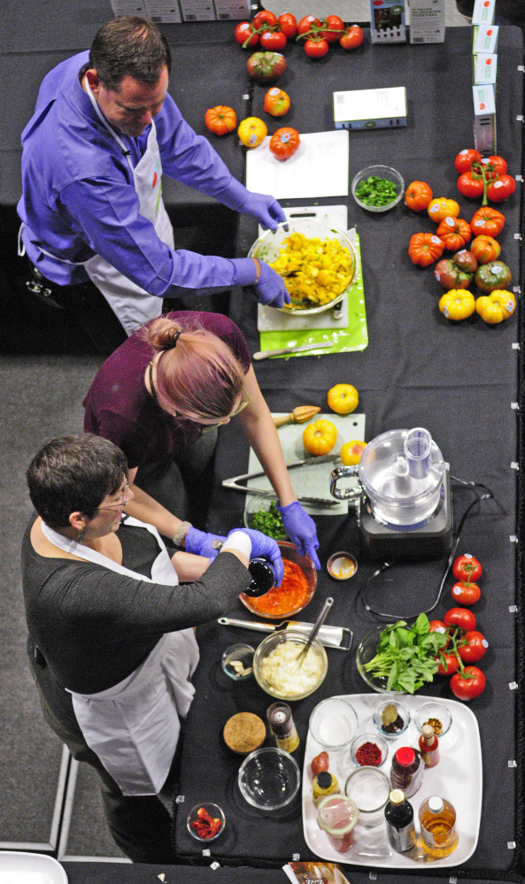 Cynthia Finnemore-Simonds, bottom left, Elizabeth Simonds and Jim Darroch, Backyard Farms director of marketing, do a cooking demonstration featuring Backyard Farms tomatoes during the Maine Agricultural Trades Show in Augusta in January 2017. Representatives of the U.S. Department of Agriculture won’t be attending an agriculture trade show in Maine next week because of the partial government shutdown.