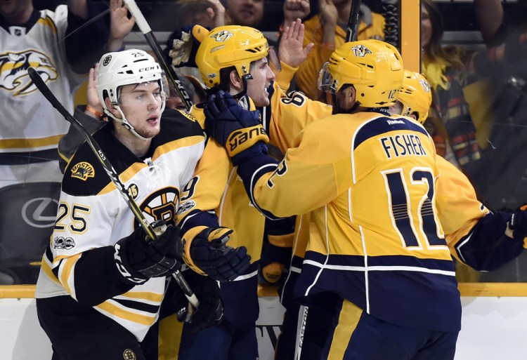 Predators left wing Filip Forsberg, center, celebrates with center Mike Fisher (12) after Forsberg scored what proved to be the game winner late in the second period. Bruins defenseman Brandon Carlo skates by after the goal.