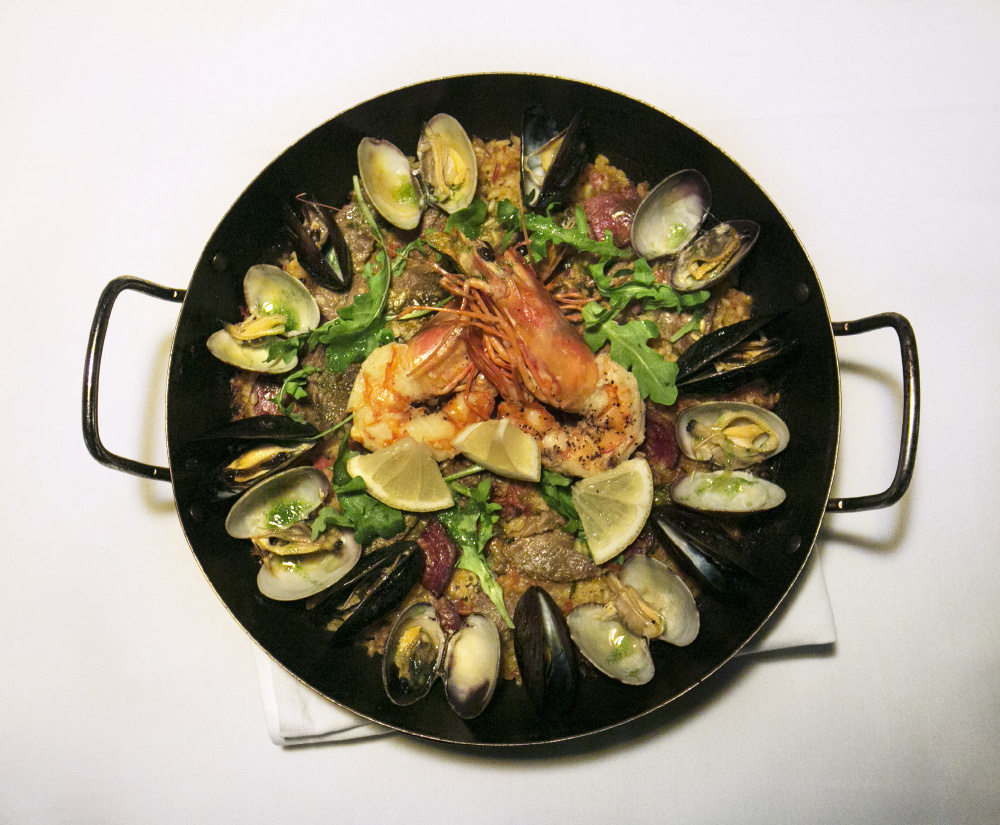 Paella de Mariscos made with calasparra rice, Spanish sofrito, chorizo, lobster, mussels, manilla clams, shrimp, arugula, garlic parsley oil and lemon wedges at Toroso in Kennebunk.