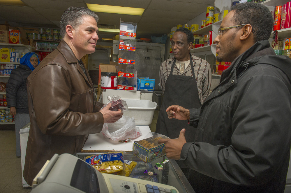 Portland Mayor Ethan Strimling talks with owner Mahdi Ahmed, right, and Ahmed Hassan, center, while shopping at the market.