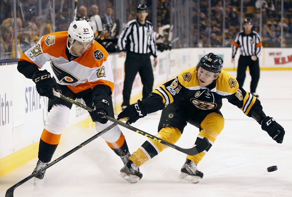 Philadelphia's Brandon Manning, left, tries to pass the puck as Boston's Anton Blidh pursues, during the first period of Saturday's game in Boston. (Associated Press/Michael Dwyer)
