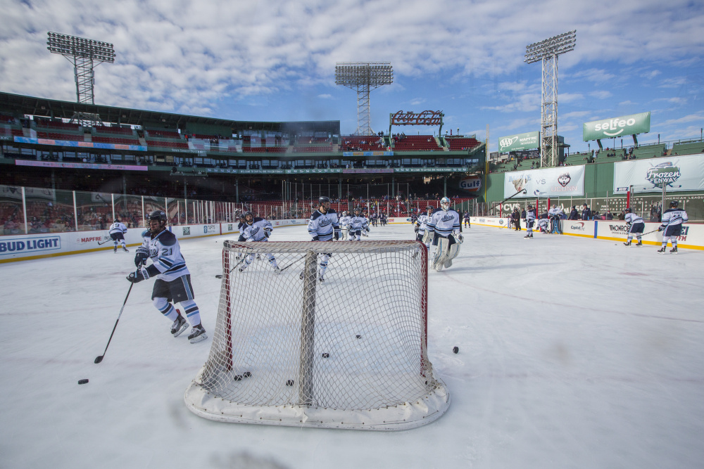With the Green Monster in the background, UMaine players warm up before the start of Saturday's game against Connecticut at Fenway Park in Boston. (Derek Davis/Staff Photographer)