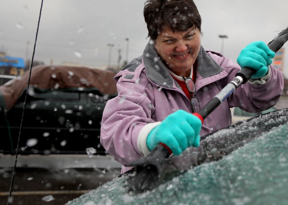 Mary Zinser scrapes a thick layer of ice off her windshield Friday in Arnold, Mo. A thick glaze of ice covered roads from Oklahoma to Illinois.