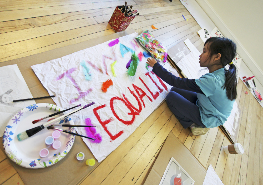 Lucy Knauft, 10, of Cape Elizabeth works on her message "I Want Equality" while making signs with her parents at 24 Preble Street on Sunday afternoon.