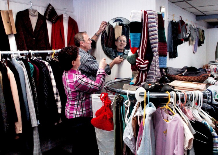Volunteers Marsha and Sonny Lagasse hang a mirror in the clothing section at the new St. Peter's Thrift Store and Food Pantry in Bingham at the former Jimmy's Market on Main Street.