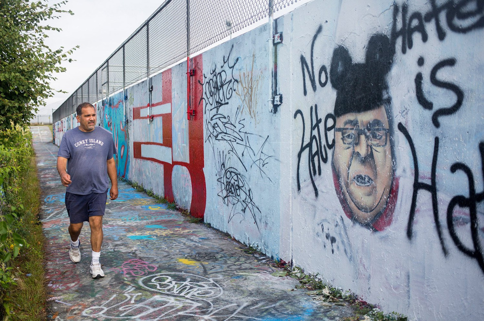 Karl Miller of Portland walks past the image of Gov. Paul LePage on the graffiti wall on Portland's Eastern Promenade last year. The Portland Water District held a public hearing Wednesday night on whether graffiti artists should continue to use the wall.