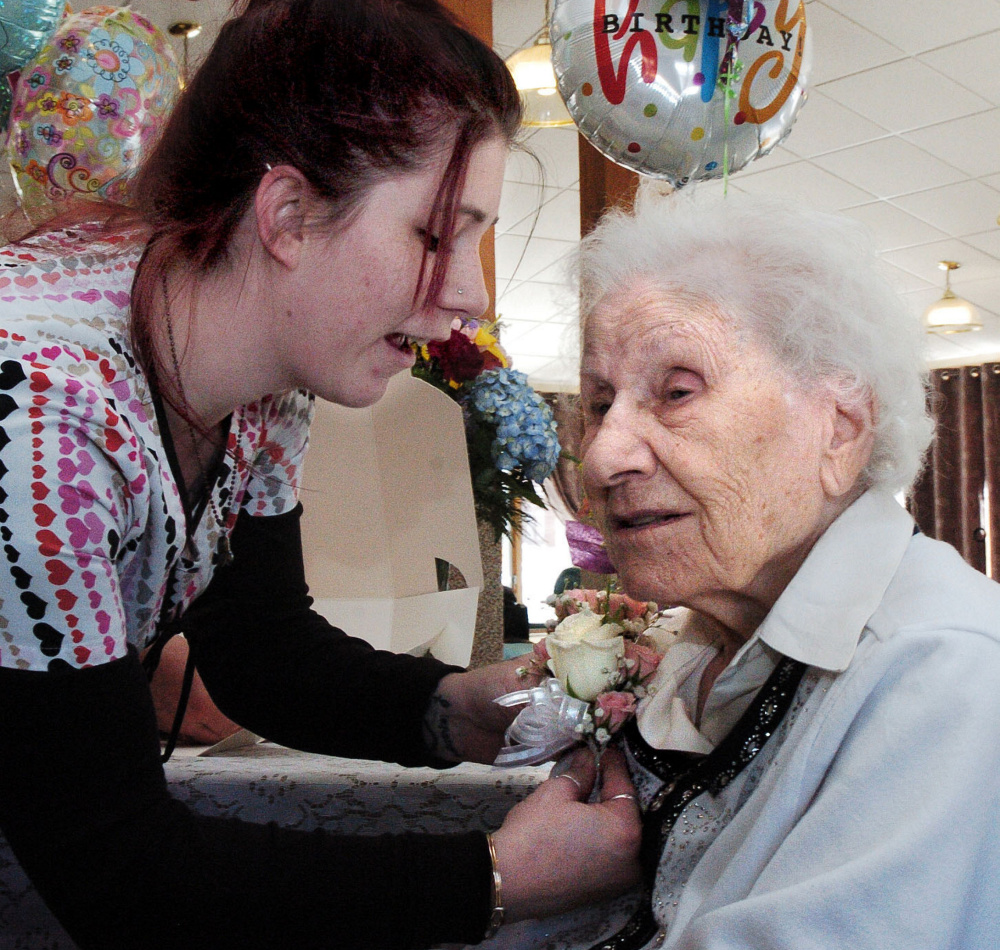 Hillary Dillingham pins a corsage on Ann Labin prior to her 100th birthday party at the Maple Crest Living Center in Madison on Monday.
