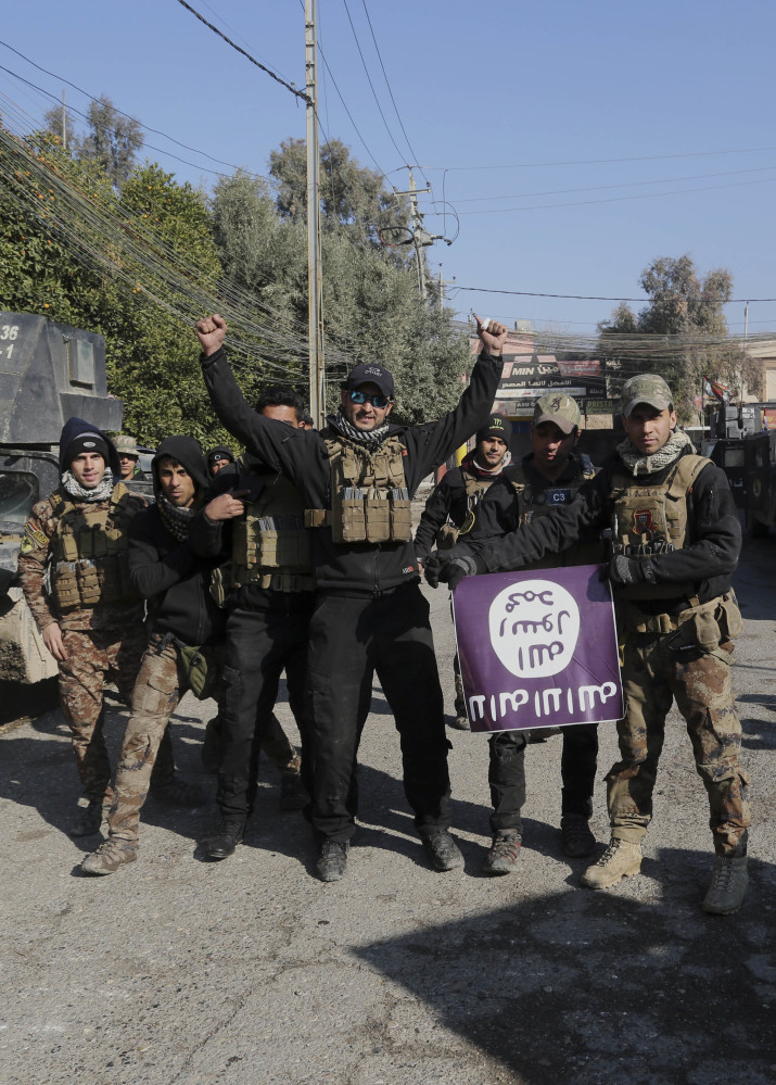 Iraqi special forces troops celebrate as they hold a flag of the Islamic State they captured after regaining control of the Andalus neighborhood on the eastern side of Mosul.