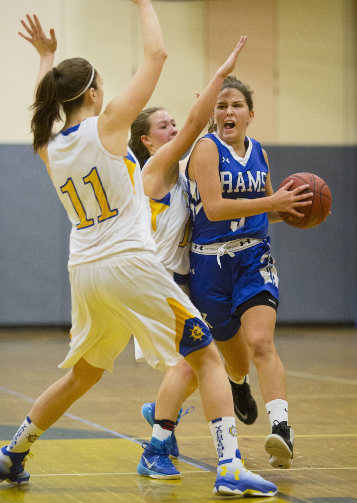 Kennebunk's Marran Oakman drives to the hoop while being guarded by Falmouth's Grace Dimmick, left, and Katie Rogers.