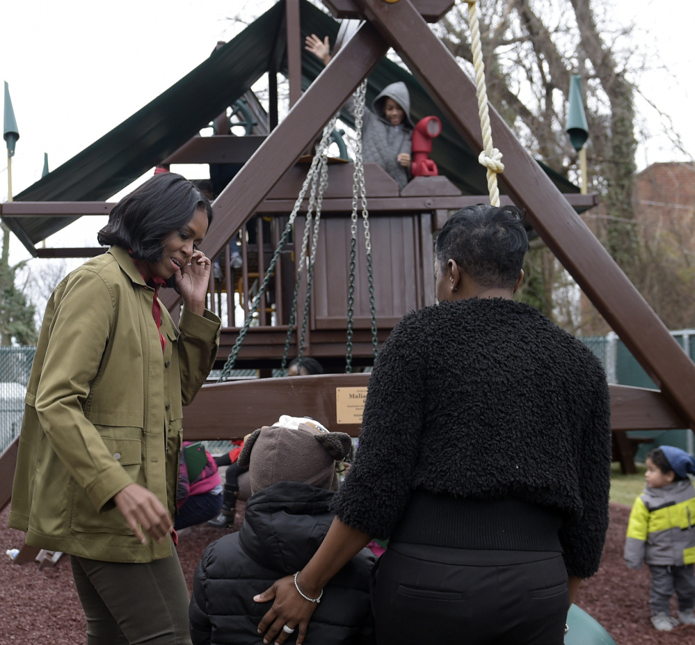 First lady Michelle Obama, left, talks with people as she and President Obama visit the playground at the family shelter in Washington on Monday.