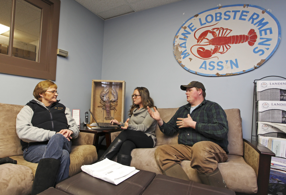 Alisha Keezer, center, a health insurance adviser, helps Cindy Welch sign up for coverage, joined by her lobsterman son, Chris Welch, at Maine Lobstermen's Association headquarters.