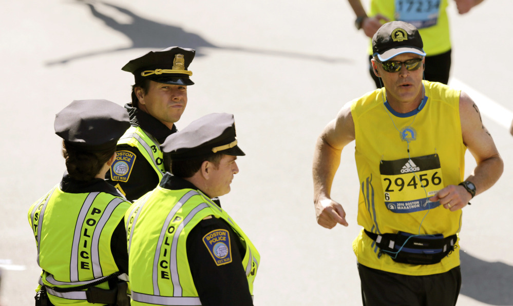 Actor Mark Wahlberg, center left, dressed as a Boston Police officer, watches runners cross the finish line as he films a scene for his "Patriot's Day" movie at the 120th Boston Marathon in Boston. "This was Boston's story," a spokeswoman said.