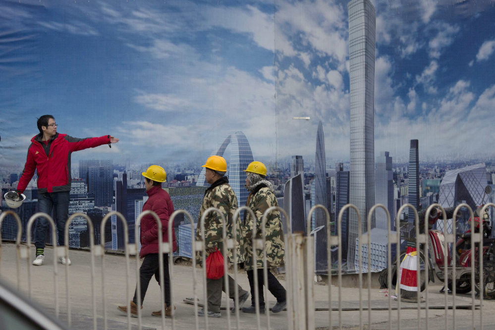 A construction worker directs others as they walk past an artist's impression of the Central Business District under construction in Beijing, China, Monday, Jan. 16, 2017. The International Monetary Fund on Monday raised its growth forecast for China but warned rising debt that has prompted concern about the country's finances increase the risk of a sharper slowdown. (AP Photo/Ng Han Guan)
