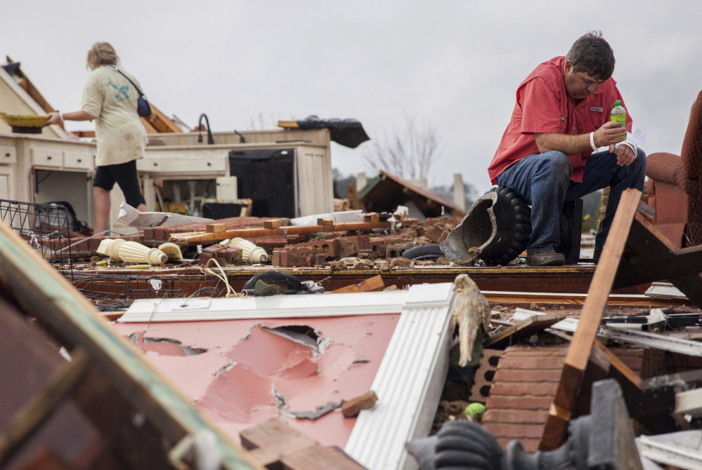 Jeff Bullard sits in what used to be the foyer of his home as his daughter Jenny Bullard looks through debris after their house was severely damaged by a tornado early Sunday in Adel, Ga.