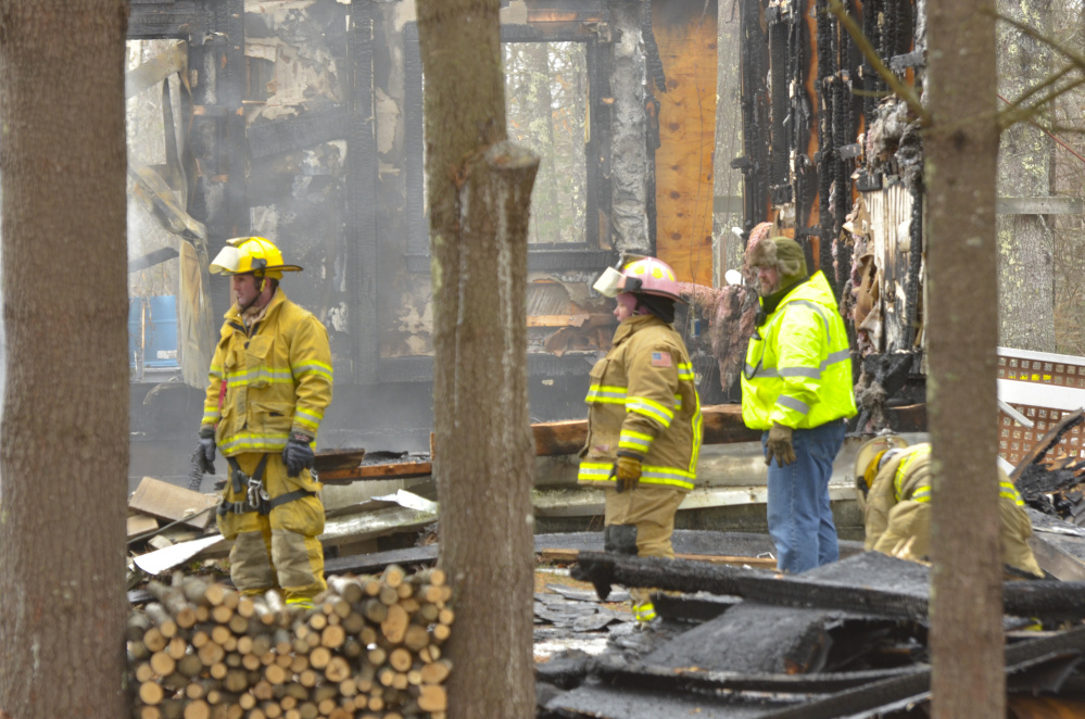 Firefighters walk through remnants of the house that was destroyed Monday in an early morning fire that left two dead in the town of Washington.