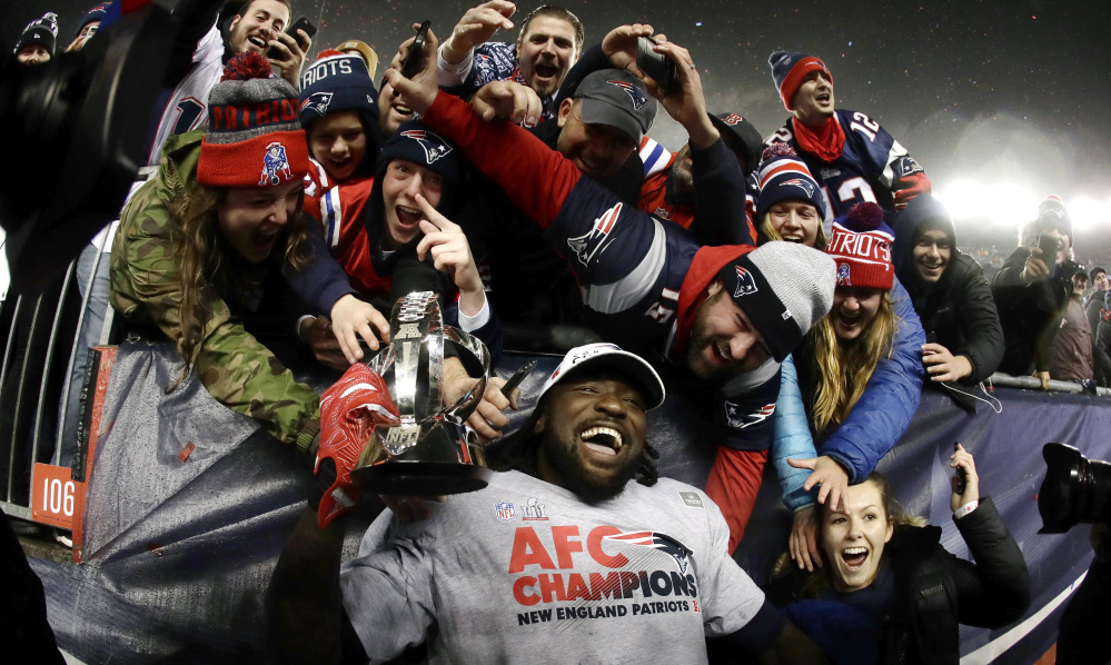 Patriots running back LeGarrette Blount holds the AFC championship trophy surrounded by fans after the Patriots defeated the Pittsburgh Steelers on Sunday night to advance to the Super Bowl.