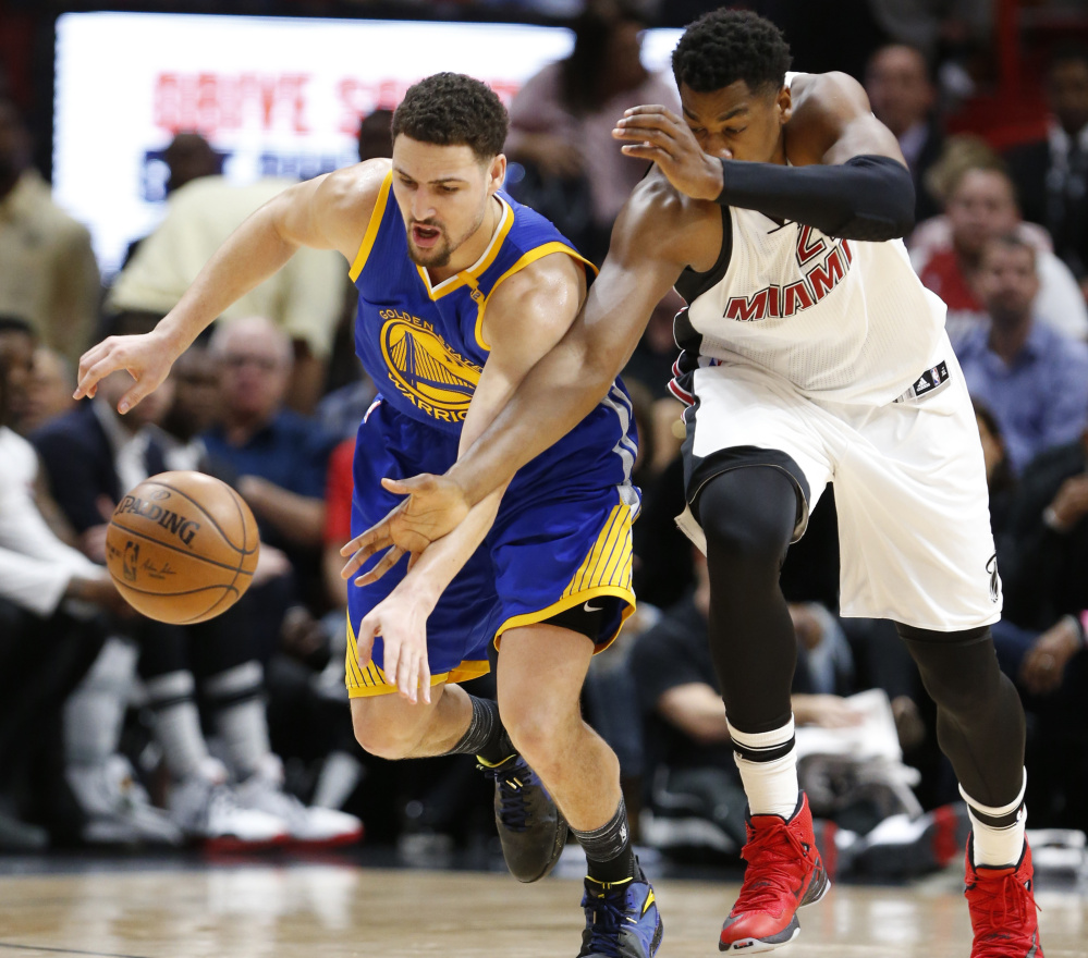 Golden State Warriors guard Klay Thompson, left, and Miami Heat center Hassan Whiteside battle for a loose ball during the first half of a 105-102 win by the Heat Monday night at Miami.