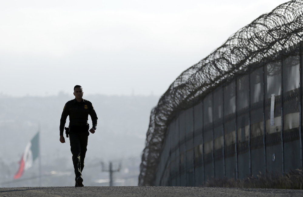 A Border Patrol agent Eduardo Olmos walks near the secondary fence separating Tijuana, Mexico, background, and San Diego in San Diego last June. The Border Patrol chief has left his job.