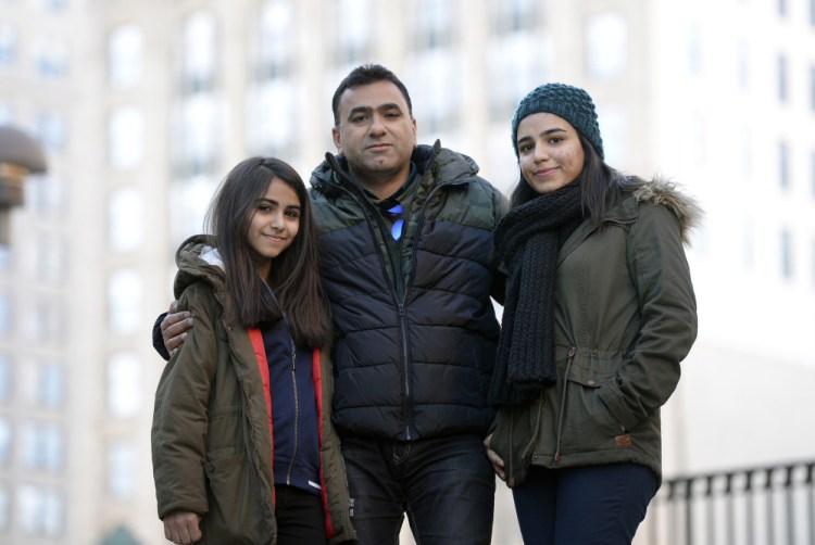 Labed Alalhanfy 49, an Iraqi refugee, with his daughters Omaima 13, left, and Jumana, 19, in Portland's Monument Square on Saturday. They're waiting anxiously to find out whether a third daughter, 20-year-old Bananh, can come to the United States.