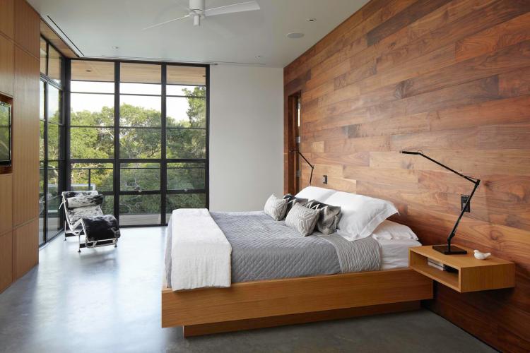 Walnut planks cover the feature wall of a master bedroom in Austin, Texas.