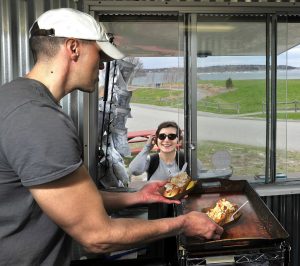 Karl Sutton of South Portland runs the Bite Into Maine food truck with his wife, Sarah, and serves two lobster rolls to another customer at Fort Williams Park.