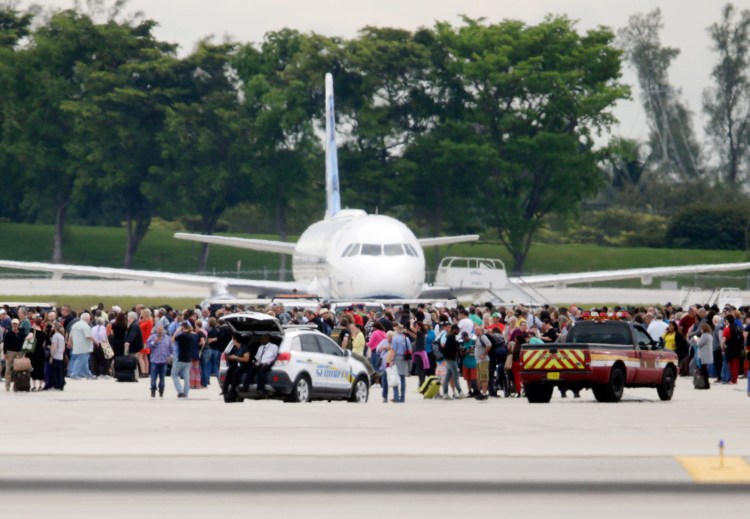 People stand on the tarmac at Fort Lauderdale-Hollywood International Airport on Friday after a man opened fire inside a terminal, killing five people and wounding eight before being taken into custody. 