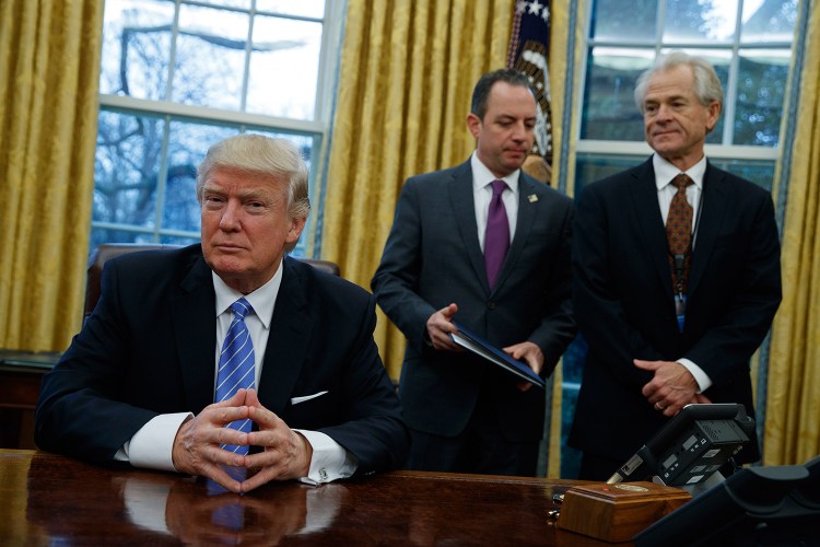 National Trade Council adviser Peter Navarro, right, and White House Chief of Staff Reince Priebus, center, wait for President Donald Trump to sign three executive orders Monday in the Oval Office. 