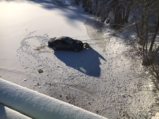 A car rests on the ice of the Saco River in Hiram after plunging over a bank on Sunday.