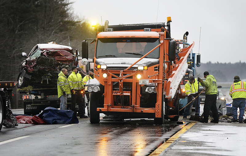 Workers clean up the scene where a pickup truck crashed into the back of a snowplow in Wells on Friday.