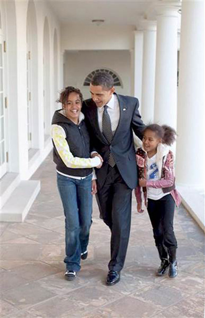 President Obama walks down the White House Colannade with his two daughters in this undated White House photo.