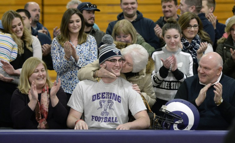 Raffaele Salamone of Deering High receives a kiss from his grandmother, Dianne Salamone, after signing a letter of intent Wednesday to play football at the University of Maine. Salamone's mother, Anne Salamone, left, and his father, Vinnie, applaud the signing.