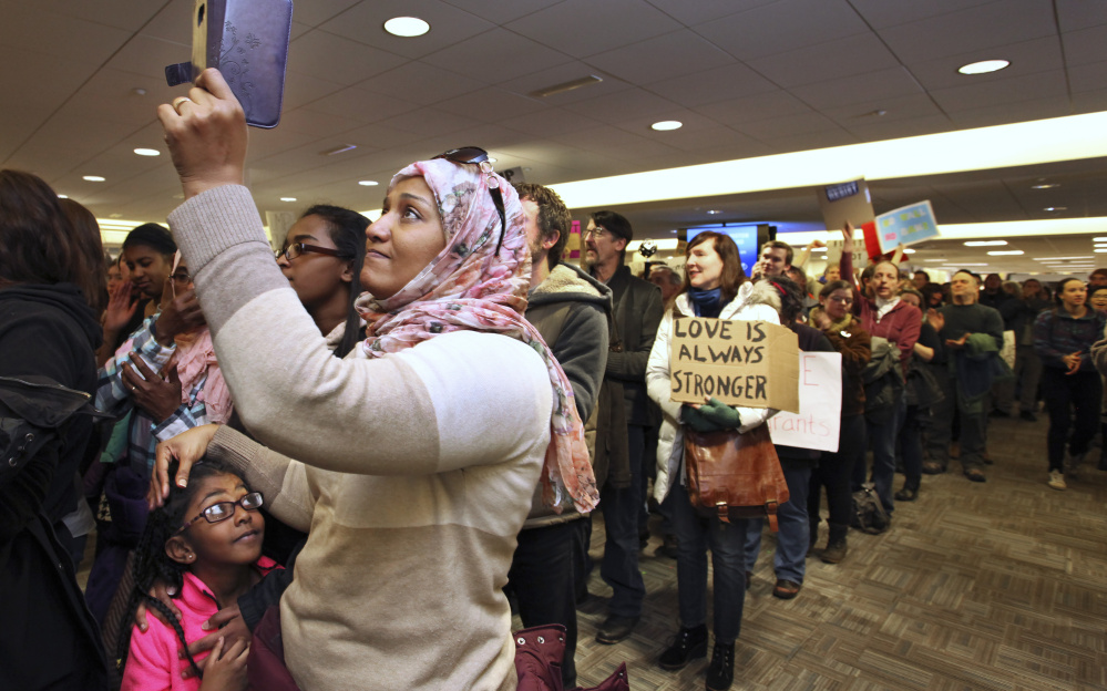 At the Portland International Jetport on Sunday, people protest entry restrictions for certain immigrants. The policy caused confusion at airports and has negative implications for Maine's economy.