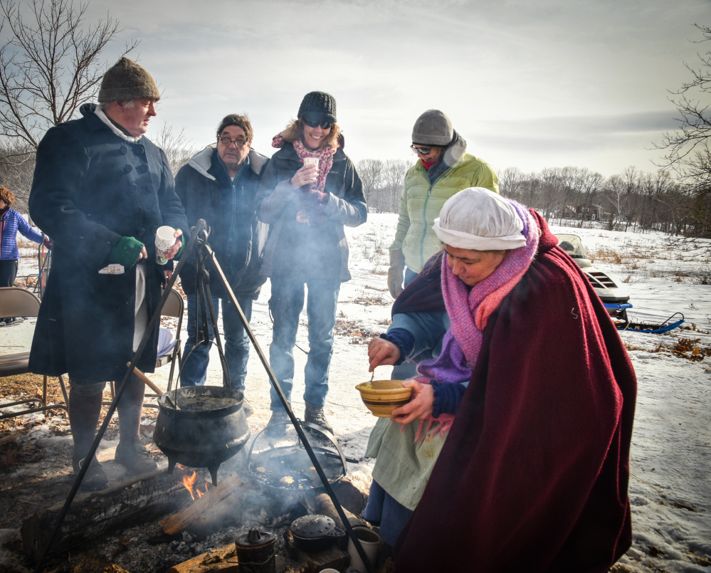 Stanley Novak, left, and Susan Reidy, right, members of historic Old Fort Western in Augusta, wear traditional winter outerwear and serve up butter bean soup and johnnycakes as part of the Viles Arboretum tour.