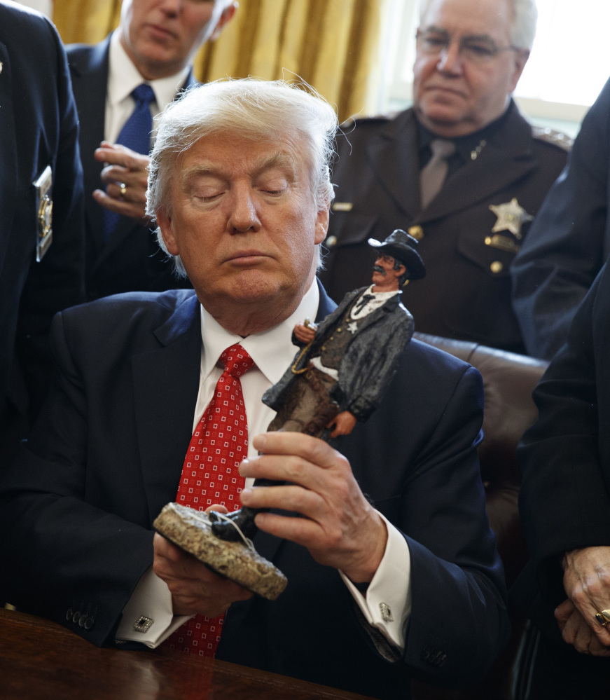 President Trump regards a gift from a group of sheriffs Tuesday. "People in uniform tend to like me," he told the sheriffs, referring to the election. "The numbers were staggering."
