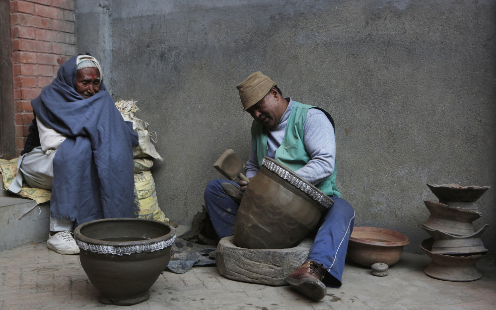 Potter Bishnu Bahadur Prajapati, 53, works on a clay pot, as a neighbor looks on in the Nepali town of Thimi. Potters used to travel to sell their wares, but that tradition is dead.