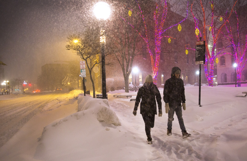 Cara Benge, left, and Nate Mosseau walk during the early hours of the blizzard Sunday evening in an almost deserted downtown Portland. They were going to meet friends after seeing Oscar film shorts.