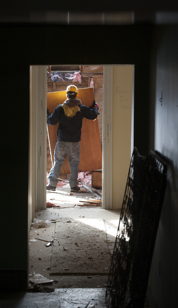 A worker employed by Barn Boards and More removes a door last week on the second floor of 18 Dennis St. in Gardiner, the former estate of Frank E. Boston.