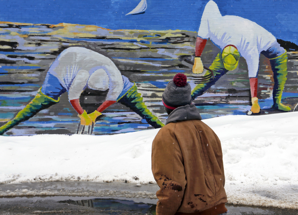 Above, clammers appear to be digging in fresh snow piles in artist Susan Bartlett Rice's mural as Larry Mundu of Portland navigates the streets. At top, a Kennebunk stop sign coated in heavy wet snow carries a double meaning Thursday morning as Mainers dug out for the third time in a week.