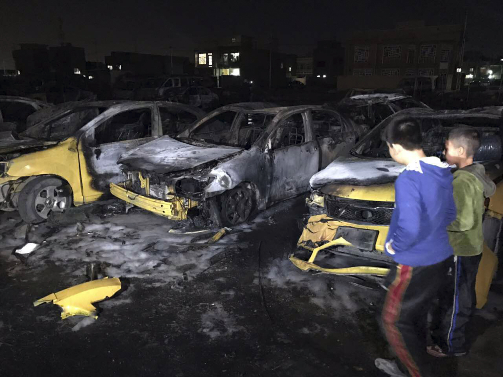 Children gather at the site of a car bomb in a used car dealer's parking lot in the southwestern al-Bayaa neighborhood in Baghdad, Iraq, on Thursday. Dozens of people were killed and wounded.