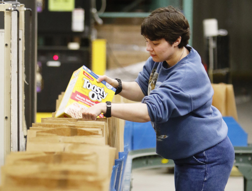 Jessica Woods, a volunteer at Good Shepherd Food Bank's Auburn warehouse, packs bags for Maine seniors who receive Supplemental Nutrition Assistance Program benefits. Over half of the Mainers who use food pantries also get SNAP, a new survey has found.