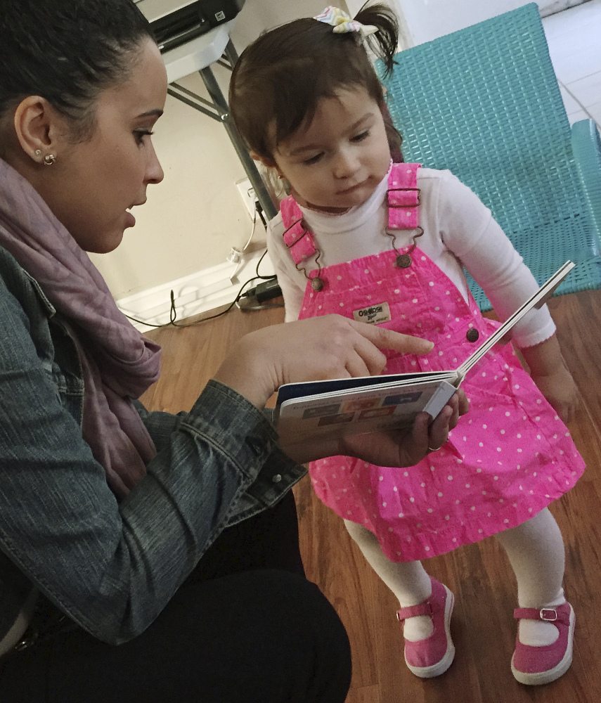 Stephanie Taveras reads a book to Gracey Niebla in Providence, R.I. The city is in the third year of boosting language skills for children from low-income families.