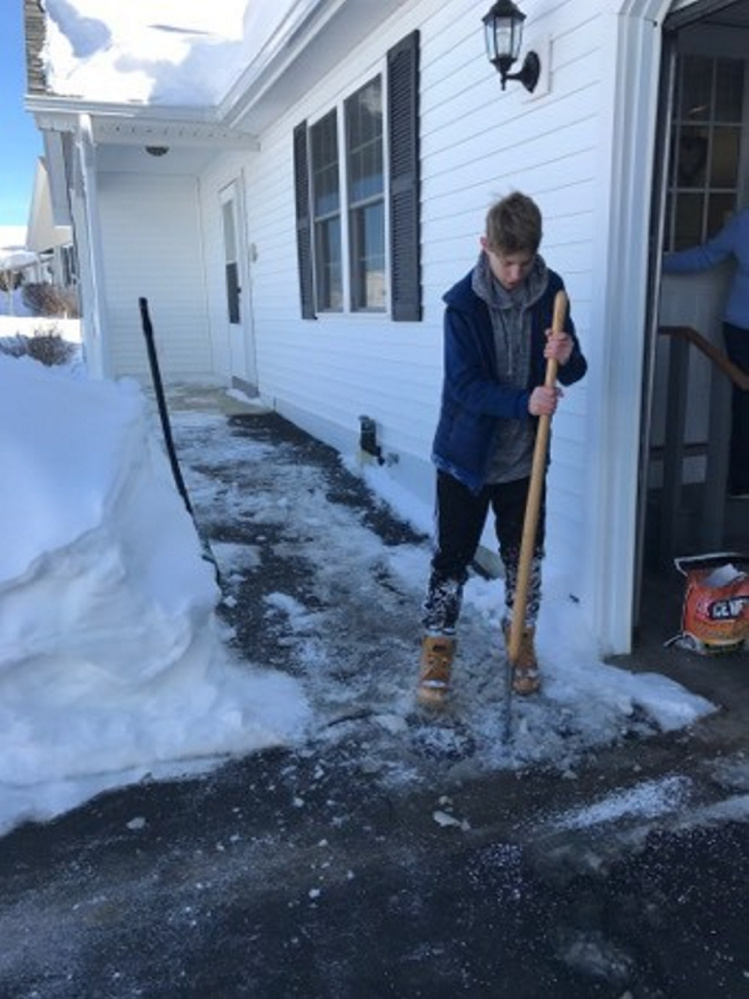 Hunter Gagne, 13, picks away at ice Friday in front of Eisa Thibeau's condominium in Winslow.