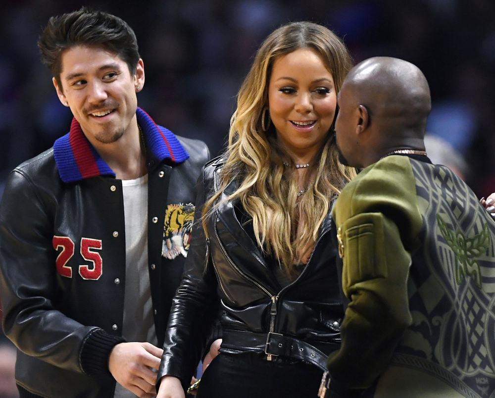 Mariah Carey talks with boxer Floyd Mayweather Jr., right, as her boyfriend, Bryan Tanaka, stands nearby at an NBA game Wednesday in Los Angeles.