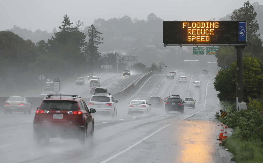A sign warns motorists of flooding Monday on northbound Highway 101 in Corte Madera, Calif. Heavy downpours are swelling creeks and rivers and bringing threats of flooding in the state's already soggy northern and central regions.