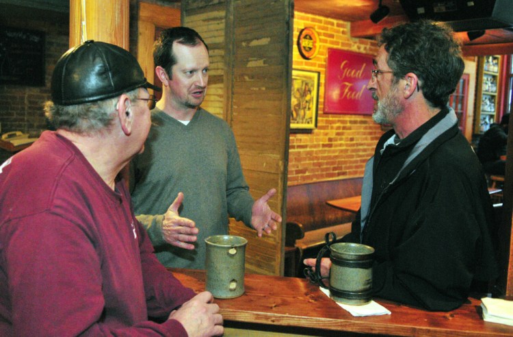 Kurt Leonard, left, and Leo Fecteau chat with front-of-house manager Casey Hynes Wednesday at the Liberal Cup in Hallowell. Hynes says the wage hike has left the pub with less money to pay nonservers.
